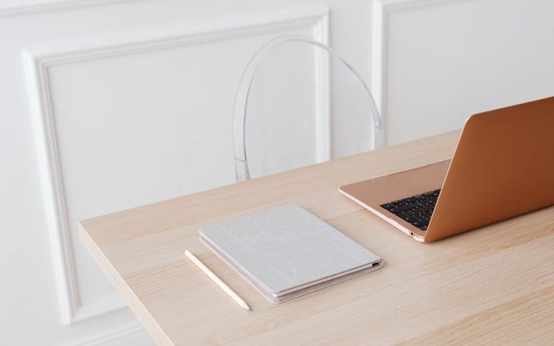 Een rustige werkplek met een laptop, een notitieboek en een potlood op een houten tafel.