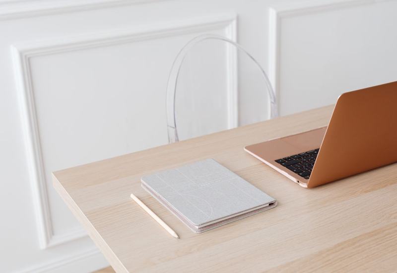 Een rustige werkplek met een laptop, een notitieboek en een potlood op een houten tafel.